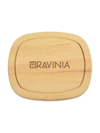 A wooden cutting board with the word RAVINIA and the Ravinia logo in it.