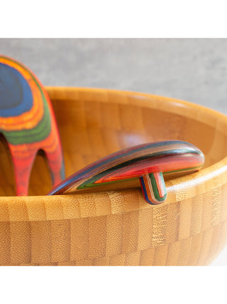 Close-up of one of the salad hands poised on the edge of a wooden bowl.