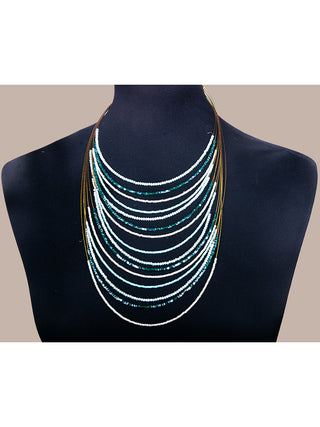 Green crystal beads on a brass wire necklace, against a black  mannequin.