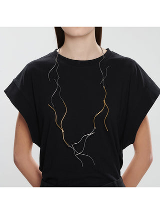 A woman in a black top wearing a two-toned necklace in brass and unfinished brass, which appears gray.