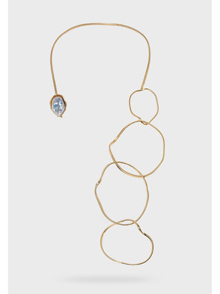 A brass collar necklace with a mother of pearl piece on the left and four loops dangling down on the right.