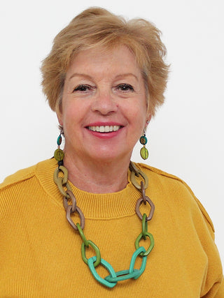 On a smiling model in a yellow top, A necklace with a lightweight wooden chain link design features an impeccable combination of green and taupe hues.