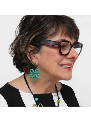 Ocean-toned earrings on a smiling model in a profile view.