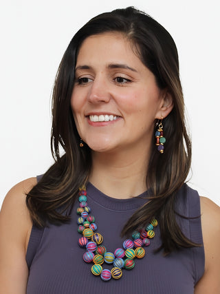 A smiling model in a purple top wearing A necklace with multicolor beads, expertly wrapped and closely knotted for a luxurious and exclusive look.