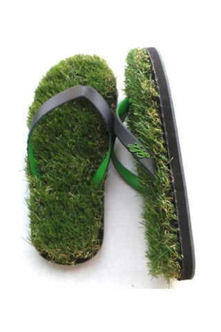 A pair of flip flops that appear to be made of grass, with green and black straps, on a white background.