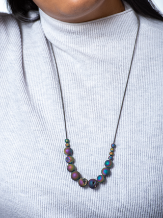 A necklace with geode beads hangs from the neck of a young woman.