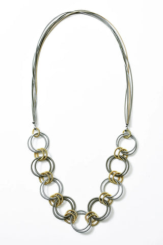 Necklace made of interlocking rings of multi-colored piano wire.