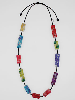 A necklace with rectangular resin beads in rainbow colors from red to blue to green to purple, on a cord..