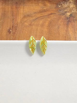 A pair of olive green leaf stud earrings with gold veins.