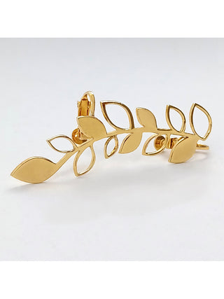 A gold earring with a leaf pattern, styled horizontally.