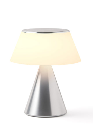 A lamp with a triangular aluminum base and an illuminated shade.