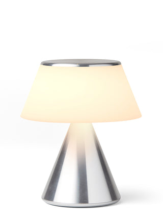 A lamp with a triangular aluminum base and an illuminated  shade.