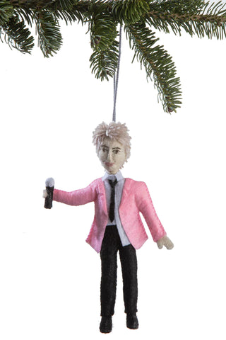 An ornament in the form of Rod Stewart with a pink blazer and microphone, under a Christmas tree branch.
