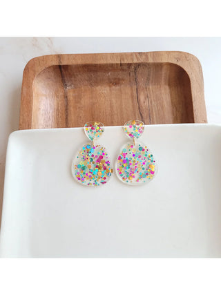 A pair of clear earrings with confetti-like glitter.
