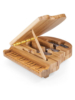 A tiny wooden piano propped open, revealing a corkscrew and cheese knives hidden inside.