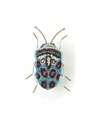 An embroidered, beaded brooch in the form of a Picasso bug, with blue, white and red coloring on its back.
