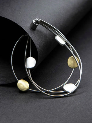 A three-strand piano wire bracelet, upright, with gold and silver-toned discs and a silver-toned magnetic clasp