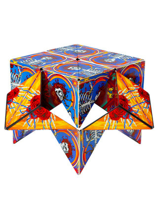 A cube with triangles at the bottom, with a design featuring the Grateful Dead's skull with roses design, in blue, orange and red.