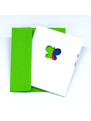 A white greeting card with a butterfly cutout in the center, in front of a green envelope.