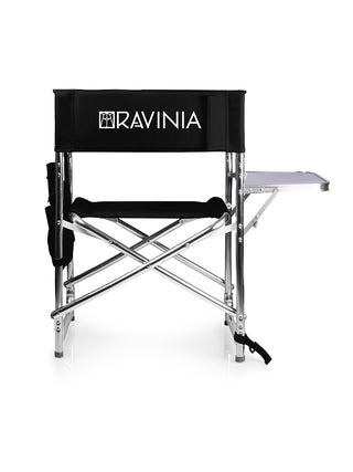 A black folding sports chair with a small side table and an armrest caddy, branded with the Ravinia logo in white.