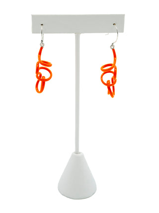 Orange twisty earrings hanging on a white earring holder.