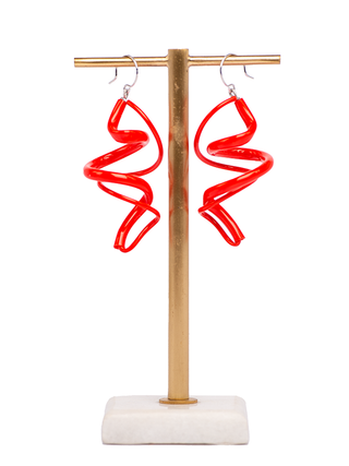 A pair of red plastic earrings with a swirling pattern, on an earring stand.