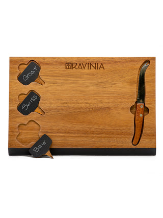 A dark wood rectangular board with the Ravinia logo across the top, a knife in a slot on the right, and three cheese signs on the left, with goat, swiss and brie written on them.
