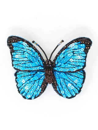 An embroidered pin in the form of a striking blue butterfly.