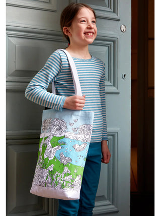 A smiling young girl with a tote decorated with butterflies slung over her shoulder.