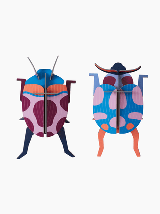 Two cardboard ladybugs, the left primarily red, and the right primarily blue.