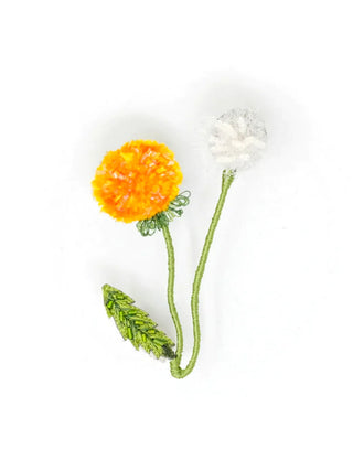 An embroidered dandelion design brooch pin, yellow on the left side and white on the right side, with green stems.