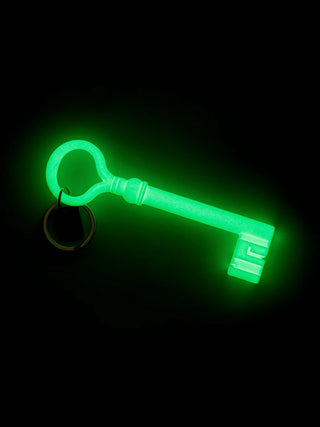 A large skeleton key with keychain, glowing green in the dark.