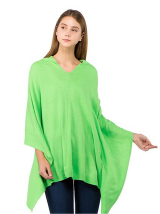 A woman in a kelly green fabric poncho, with jeans below.