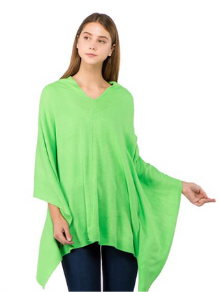A model in a kelly green fabric poncho and jeans.
