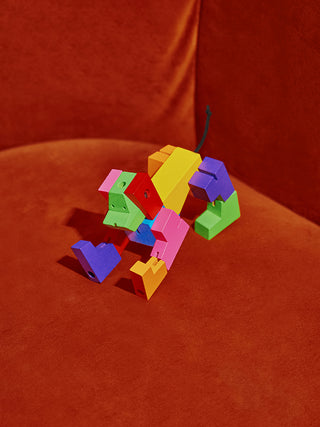 A multicolored robot dog stretched out on an orange velvet chair.