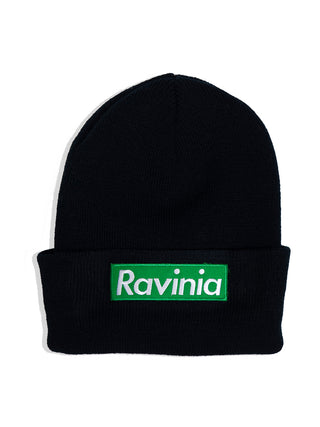 A black beanie hat, flat, with a bright green tag below the fold with RAVINIA in white letters on it.