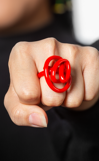 A red squiggle ring on a finger.