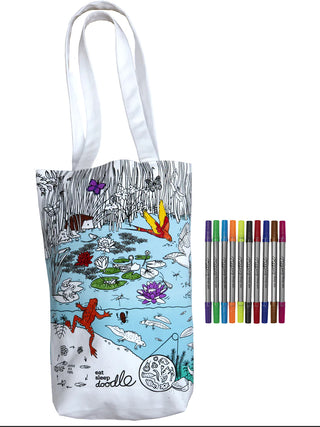 A partially colored-in pond scene on a tote bag, with markers adjacent.