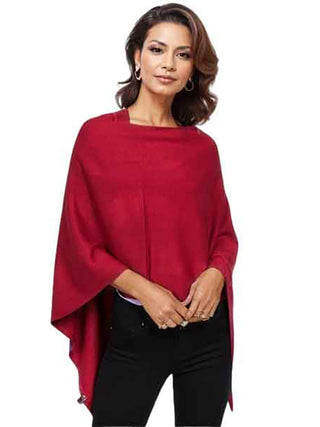 A woman wearing a burgundy knit poncho with black pants.