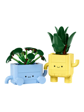 Two LEGO planters with plants and smiling faces, one blue and one yellow, on a white background.