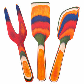 Three cheese tools made from colorful birch wood: a cheese knife, a cheese fork, and a spreader.