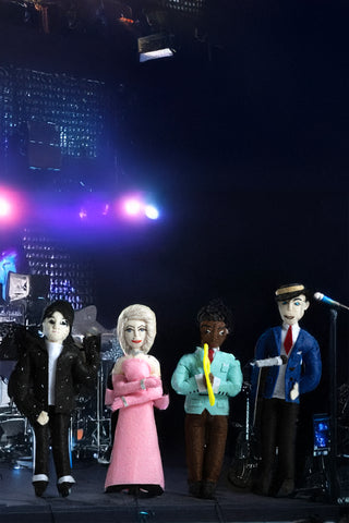 Felt ornaments representing Michael Jackson, Madonna, Louis Armstrong and Frank Sinatra on a dark stage, with spotlights behind them.