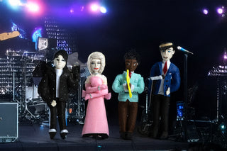 Felt ornaments representing Michael Jackson, Madonna, Louis Armstrong and Frank Sinatra on a dark stage, with spotlights behind them.