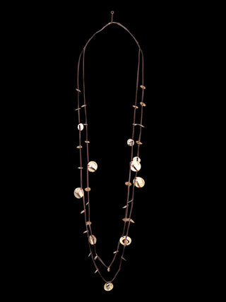 A long, doubled necklace with a gold-toned cord and bronze discs., all on a black background