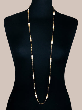 A bronze necklace with beads on gold-toned thread, posed on a black mannequin.