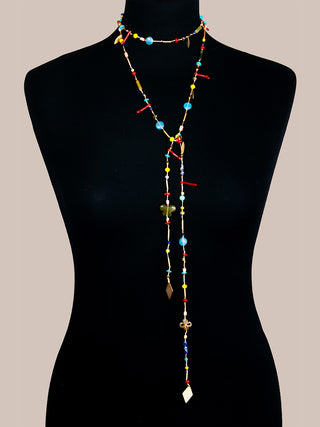 A long, twisting brass necklace with multicolored stones on a black mannequin.