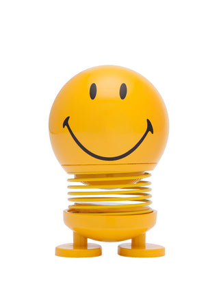 A smiling yellow figure with a round head, flat feet, and a spring in the middle.