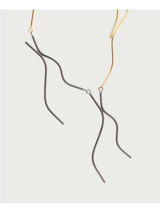 Strands of a necklace that is two-toned brass.