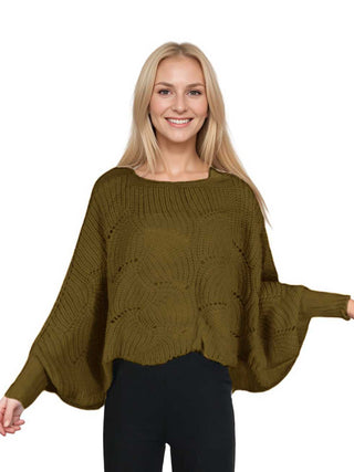 A woman wearing an olive brown knit sweater poncho with black pants.