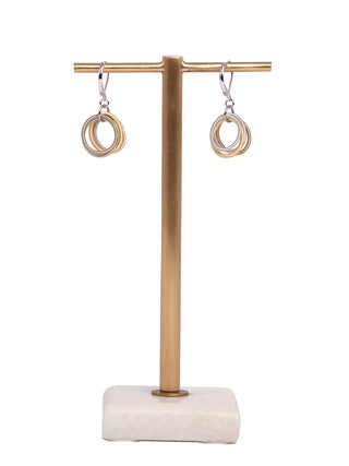 A pair of Gold and Silver Piano Wire Loop Earrings, hanging from a copper-colored bar.